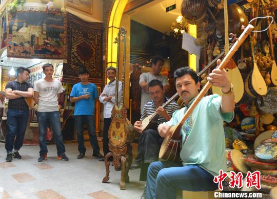 6月正值新疆旅游旺季,乌鲁木齐市国际大巴扎(市场)一处乐器摊位前,两位摊主弹起民族乐器冬不拉,用悠扬的琴声吸引游客。(摄于6月21日) 刘新 摄 6月正值新疆旅游旺季,乌鲁木齐市国际大巴扎(市场)一处乐器摊位前,两位摊主弹起民族乐器冬不拉,用悠扬的琴声吸引游客。(摄于6月21日) 刘新 摄