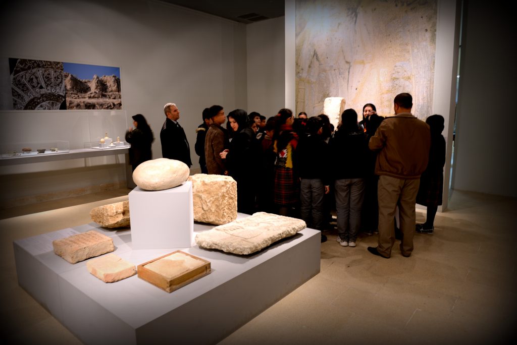 This hall of the Sulaymaniyah Museum was renovated by the UNESCO as part of a specific master-plan in 2013. The hall houses the masterpieces of the Sulaymaniyah Museum. The fragment from the wall relief which came from the North-West Palace sits on right lower angle of this wooden platform. Stamped bricks from Ur, a door sill from Kurikalzu, stone blocks from the Sassanian Paikuli Tower, and an inscribed Assyrian pavement brick are also displayed on that paltform. The visitors are gathering around the Stela of Iddi9n)-Sin, King of Simurrum. The Sulaymaniyah Museum, Iraqi Kurdistan. Photo © Osama S. M. Amin. 