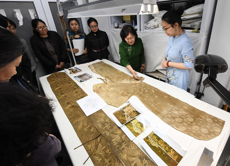 4月2日，纺织考古学家王亚蓉（右二）向与会专家学者介绍出土丝织品文物的保护情况。