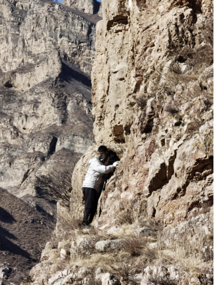 调查茶坊石窟时侧身通过陡峭的崖壁