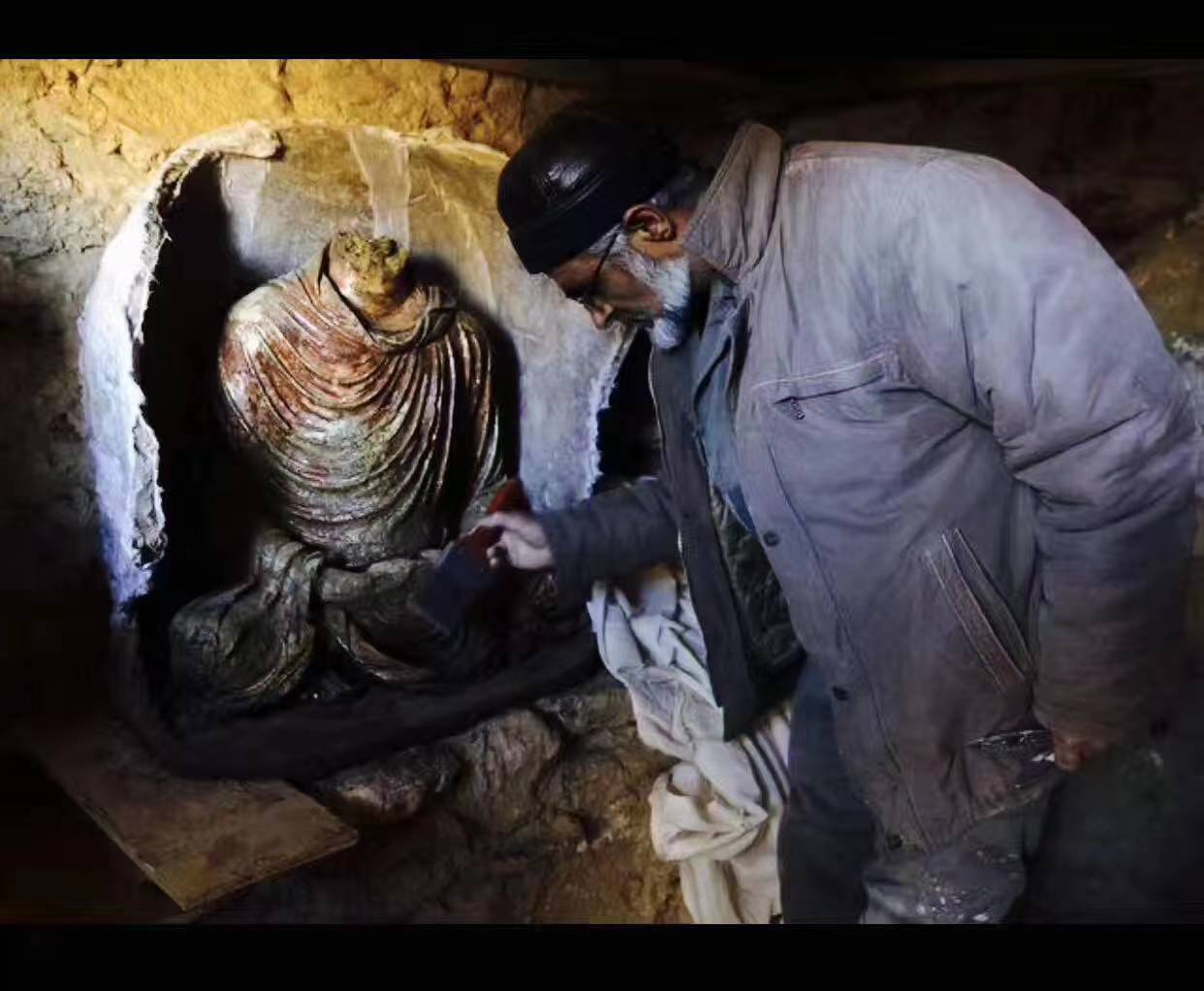 2015年2月,一位阿富汗考古学家正在清理刚从艾娜克发现的一尊无首佛像。资料 图