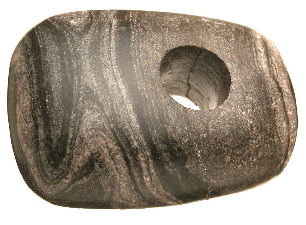 锏头,带状片麻石,苏格兰,约公元前3000年,©索尔兹伯里博物馆; 从威尔士运来的火化后的遗骸和一些陪葬品一起,被放置在巨石阵的地基坑中。